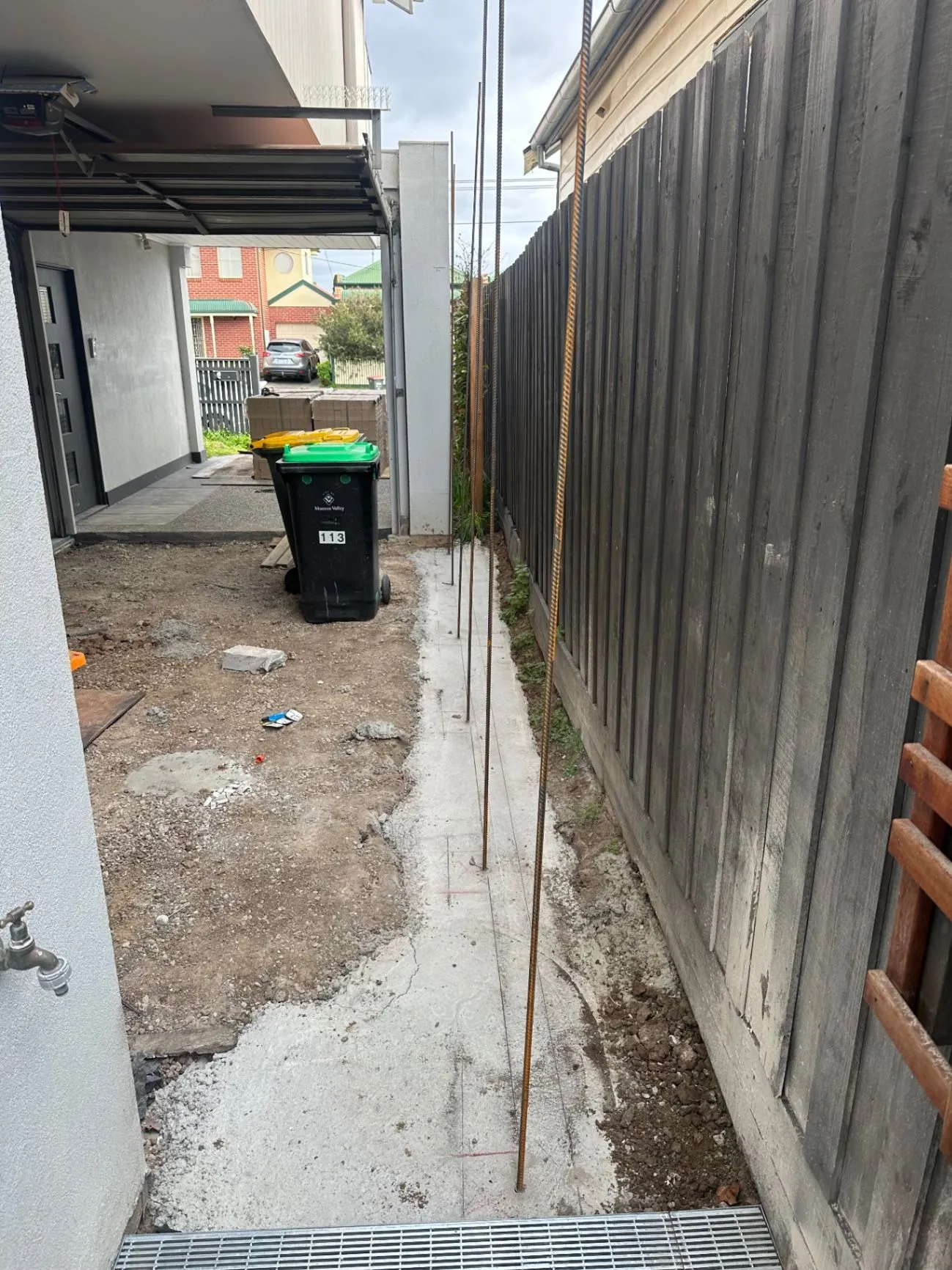 Concrete strip footing with vertical reinforcement beside a boundary fence
